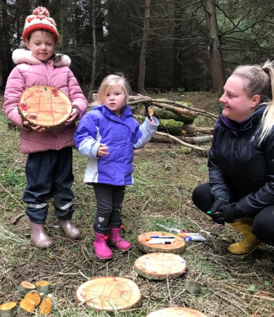 An adult and two children making crafts with wood.